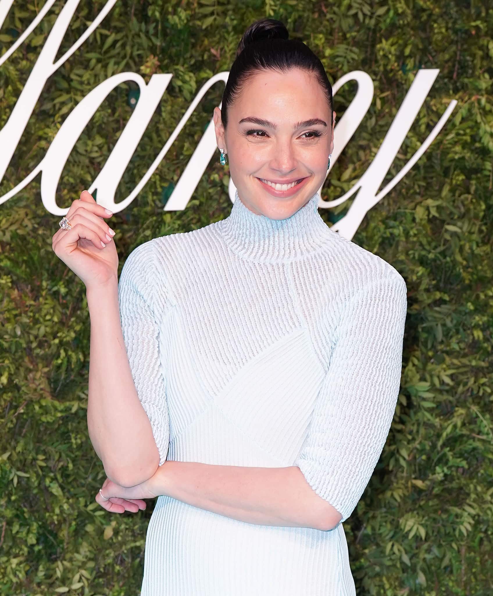 Gal Gadot styles her raven locks up into a neat bun and wears minimal makeup with brushed up brows and pink lip color