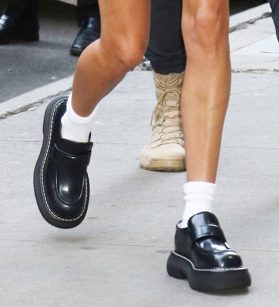 Hailey Bieber opts for a schoolgirl look as she pairs her micro mini skirt with white crew socks and Bottega Veneta loafers