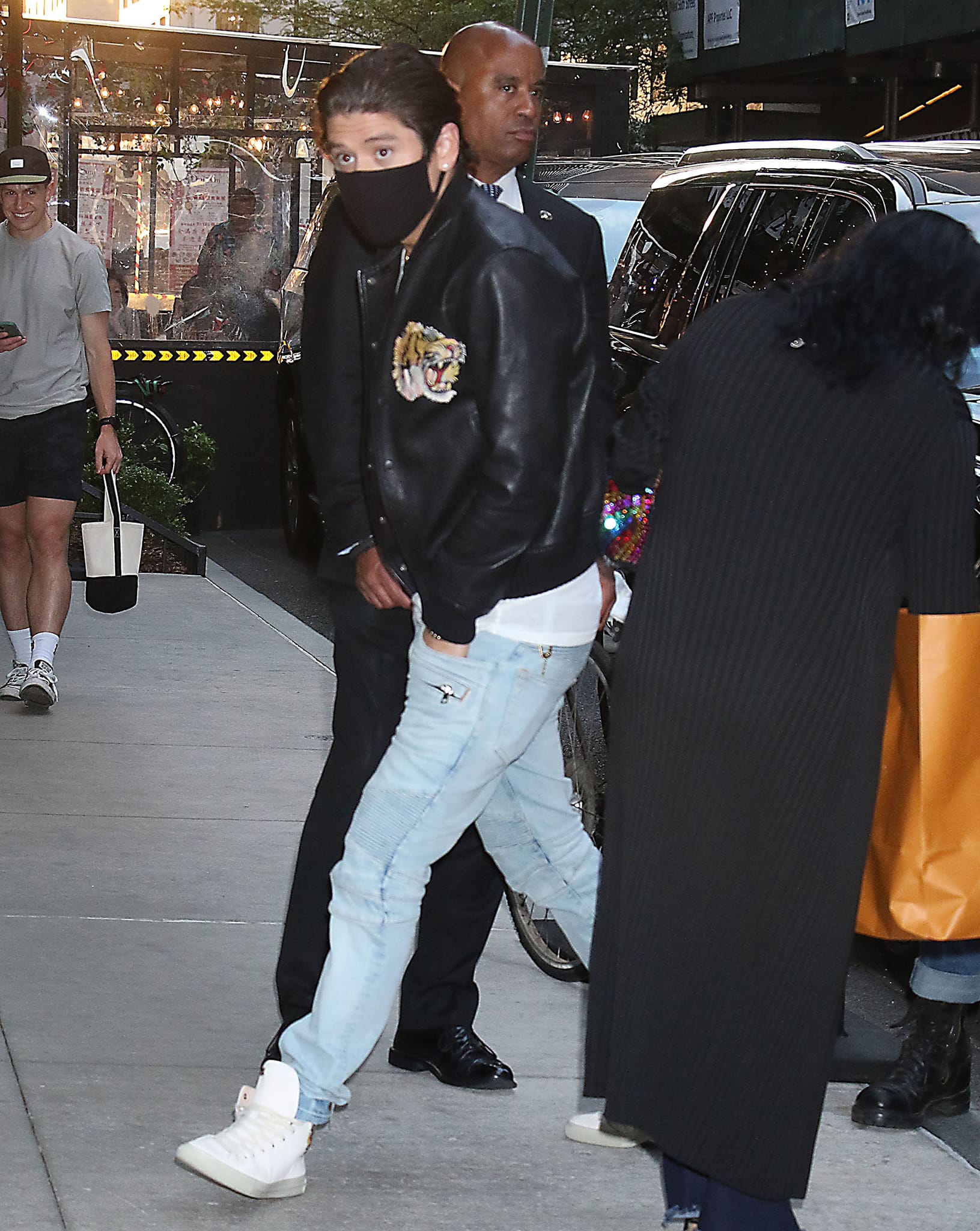 Mariah Carey's boyfriend Bryan Tanaka opts for a black letterman jacket with a white tee and light blue jeans