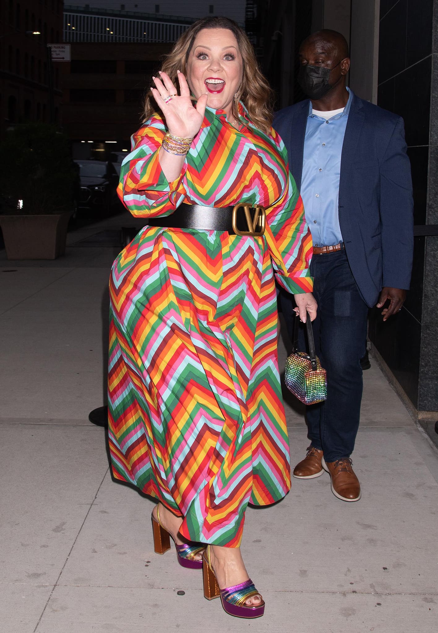 Melissa McCarthy pairs her rainbow dress with Misahara jewelry and Kurt Geiger rainbow sandals