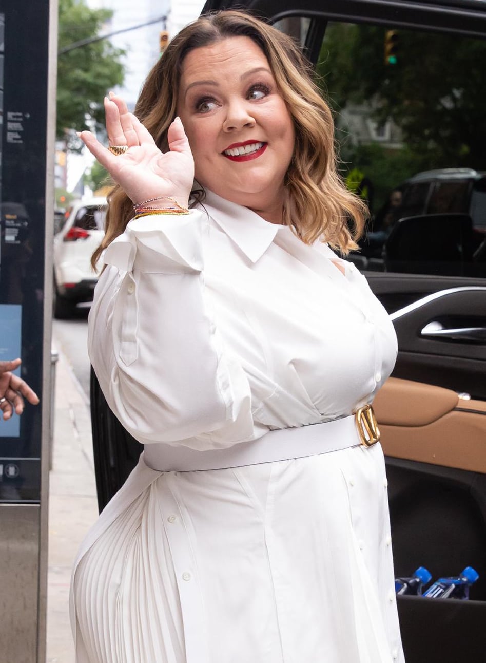 Melissa McCarthy styles her tresses in loose waves and wears a pop of red lip color