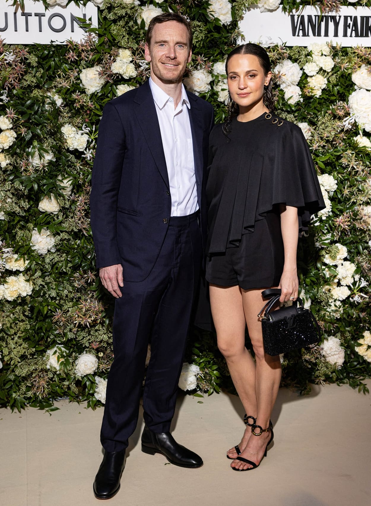 Michael Fassbender and Alicia Vikander attend the Vanity Fair x Louis Vuitton dinner during the 75th annual Cannes Film Festival, with Alicia showcasing an elegant black Louis Vuitton ensemble paired with statement heels and a sparkling handbag