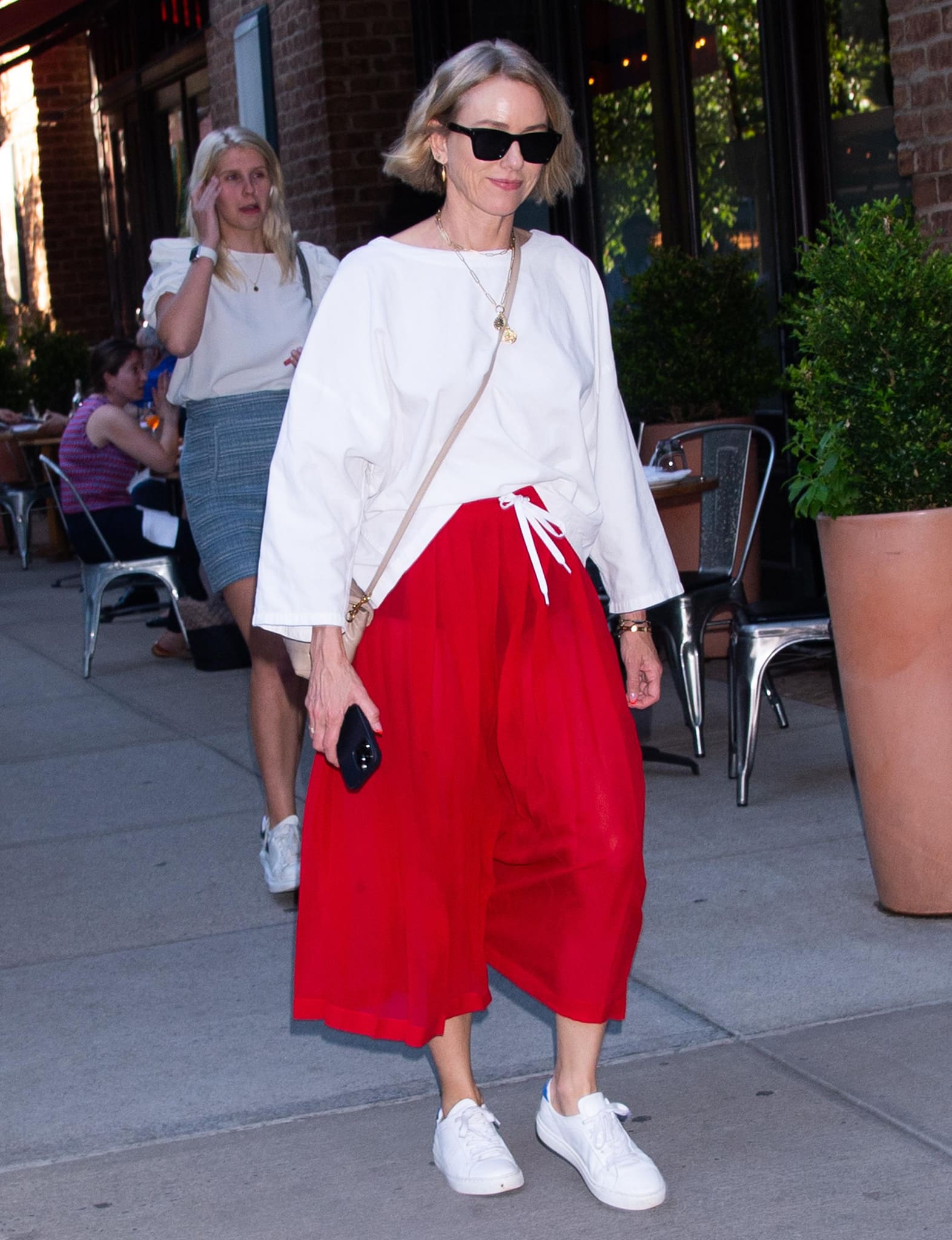 Naomi Watts shows how to wear a loose white top and a pair of floaty red culottes