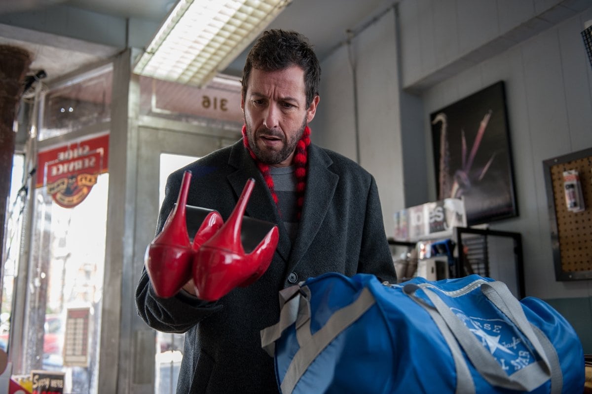 Adam Sandler as Max Simkin looking at a pair of red high heel shoes in the 2014 American magic realism comedy-drama film The Cobbler
