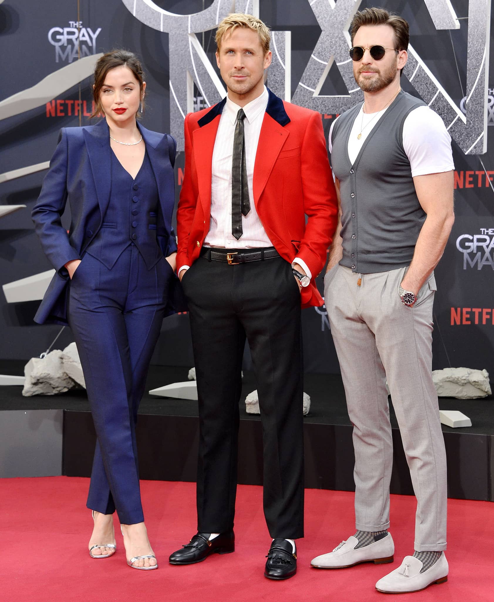 Ryan Gosling stands out in a red blazer in between Ana de Armas and Chris Evans