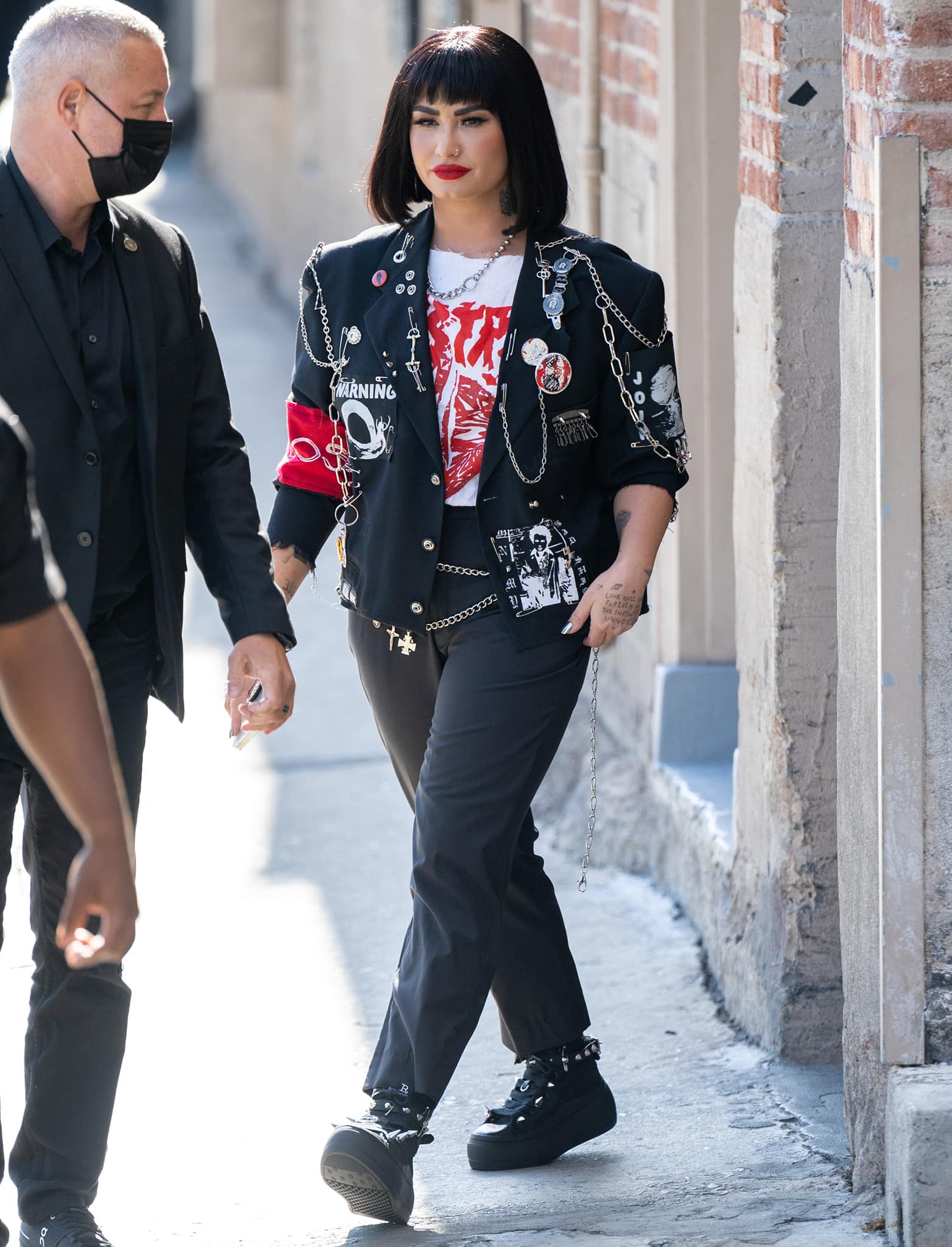 Demi Lovato opts for a rock-and-roll outfit in a graphic tee, studded jacket, matching sneakers, and black trousers