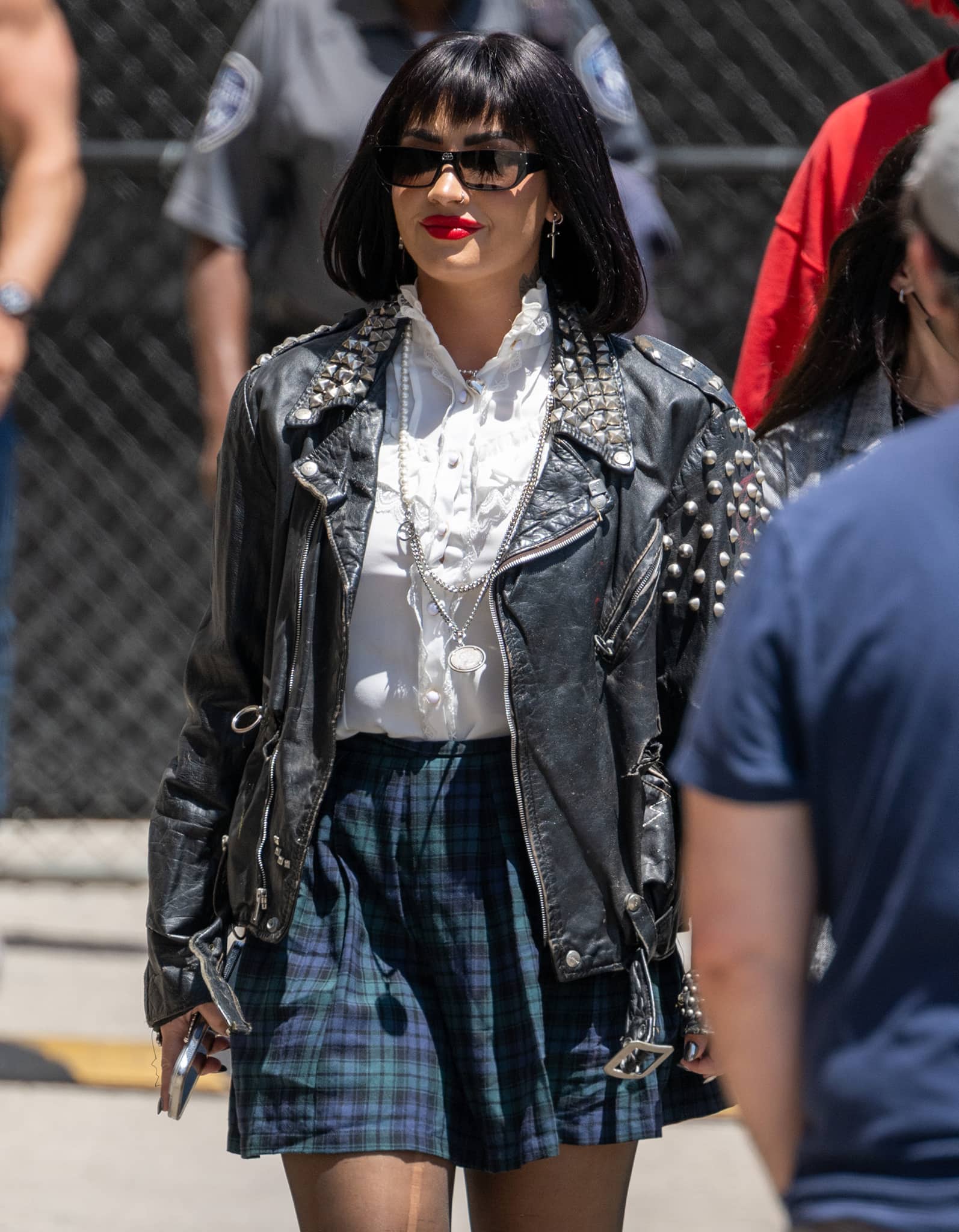 Demi Lovato styles her cool-grunge look with sunnies and long necklaces and wears a bold red lip color