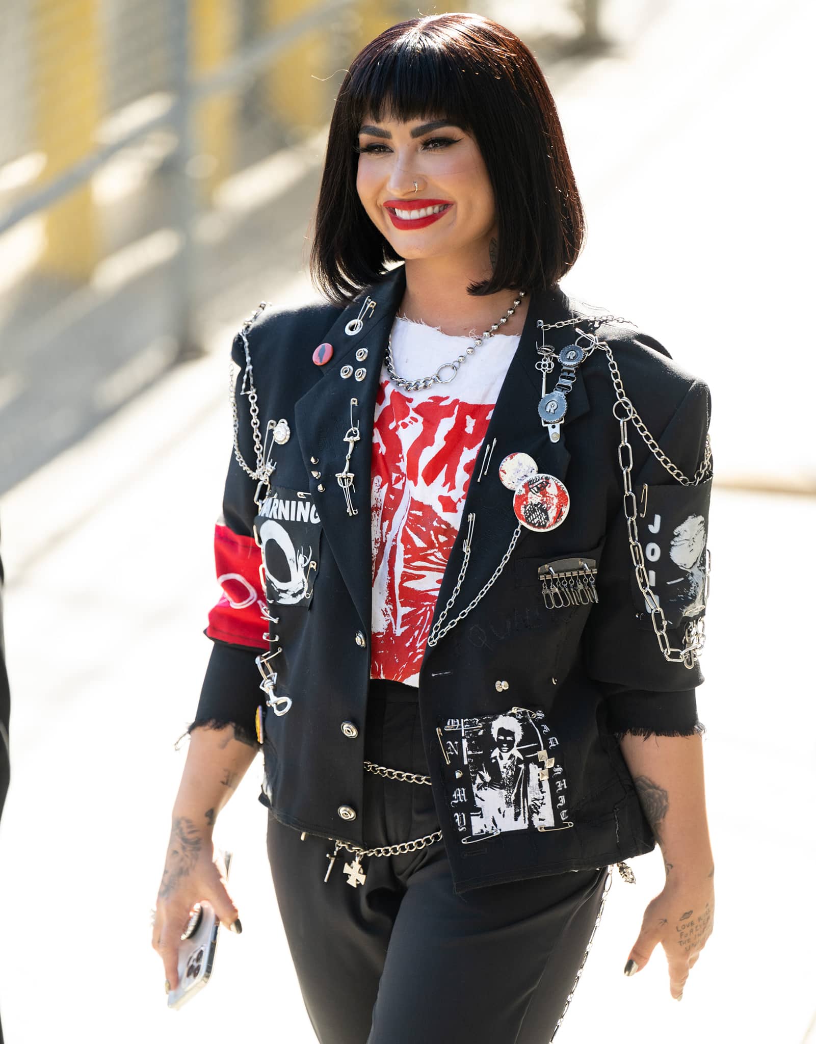 Demi Lovato wears bold red lip color and a wig with blunt bangs, covering her forehead cut