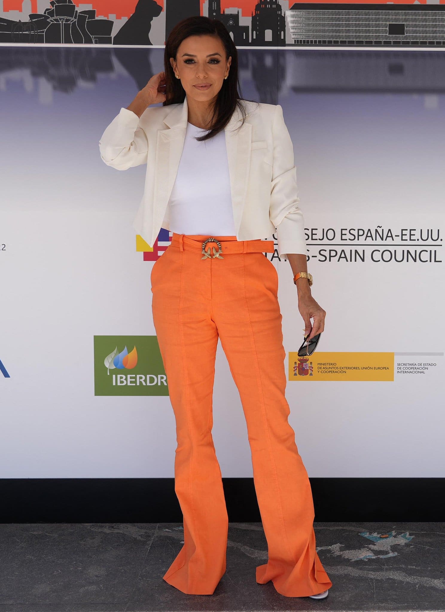 Eva Longoria is business chic in a cream blazer and a pair of orange Pinko trousers