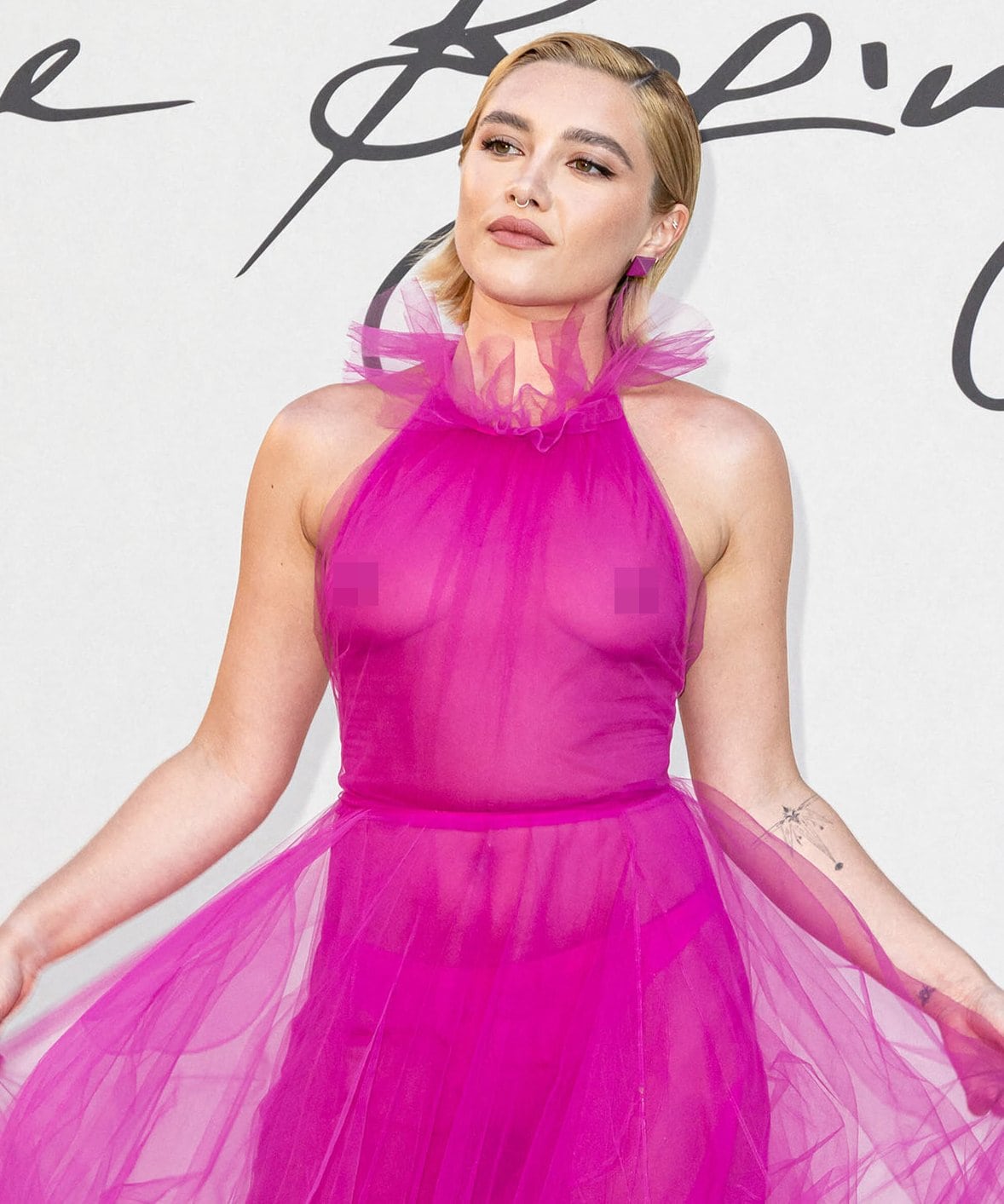 Florence Pugh wears her hair in a slick side-swept hairstyle and complements her pink gown with light pink eyeshadow and matte lipstick