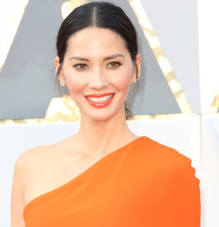 Olivia Munn in a bright orange one-shoulder Stella McCartney dress