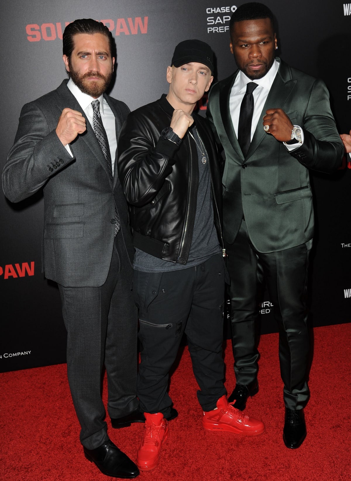 Eminem standing between a much taller Jake Gyllenhaal and 50 Cent at the Southpaw New York premiere