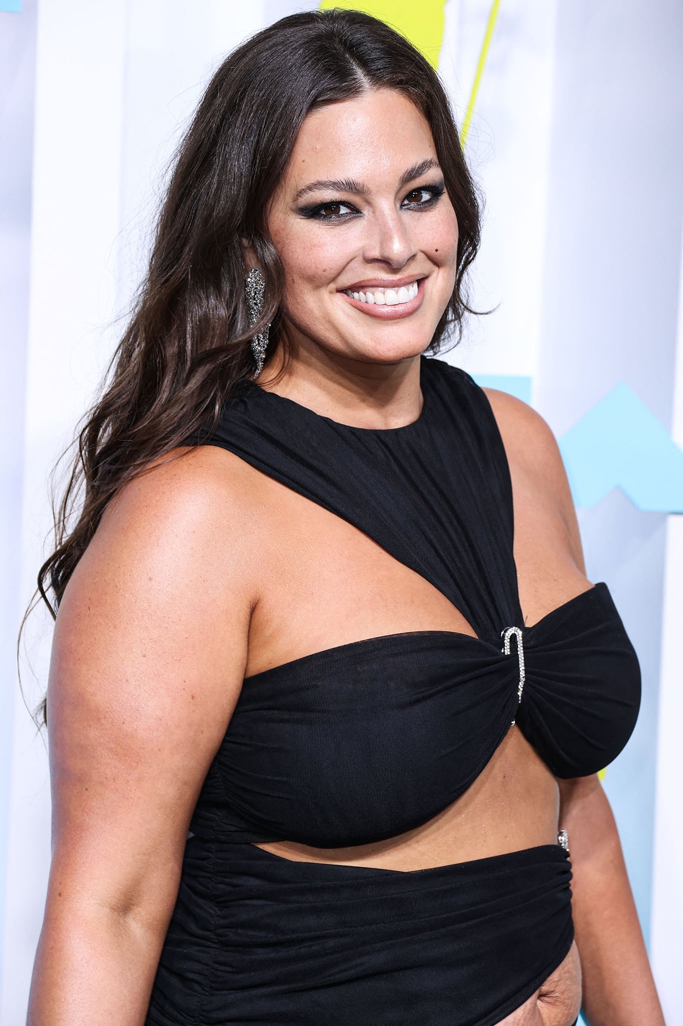 Ashley Graham amps up the glamour with dramatic smokey eye-makeup, brushed-up brows, and wavy hairstyle