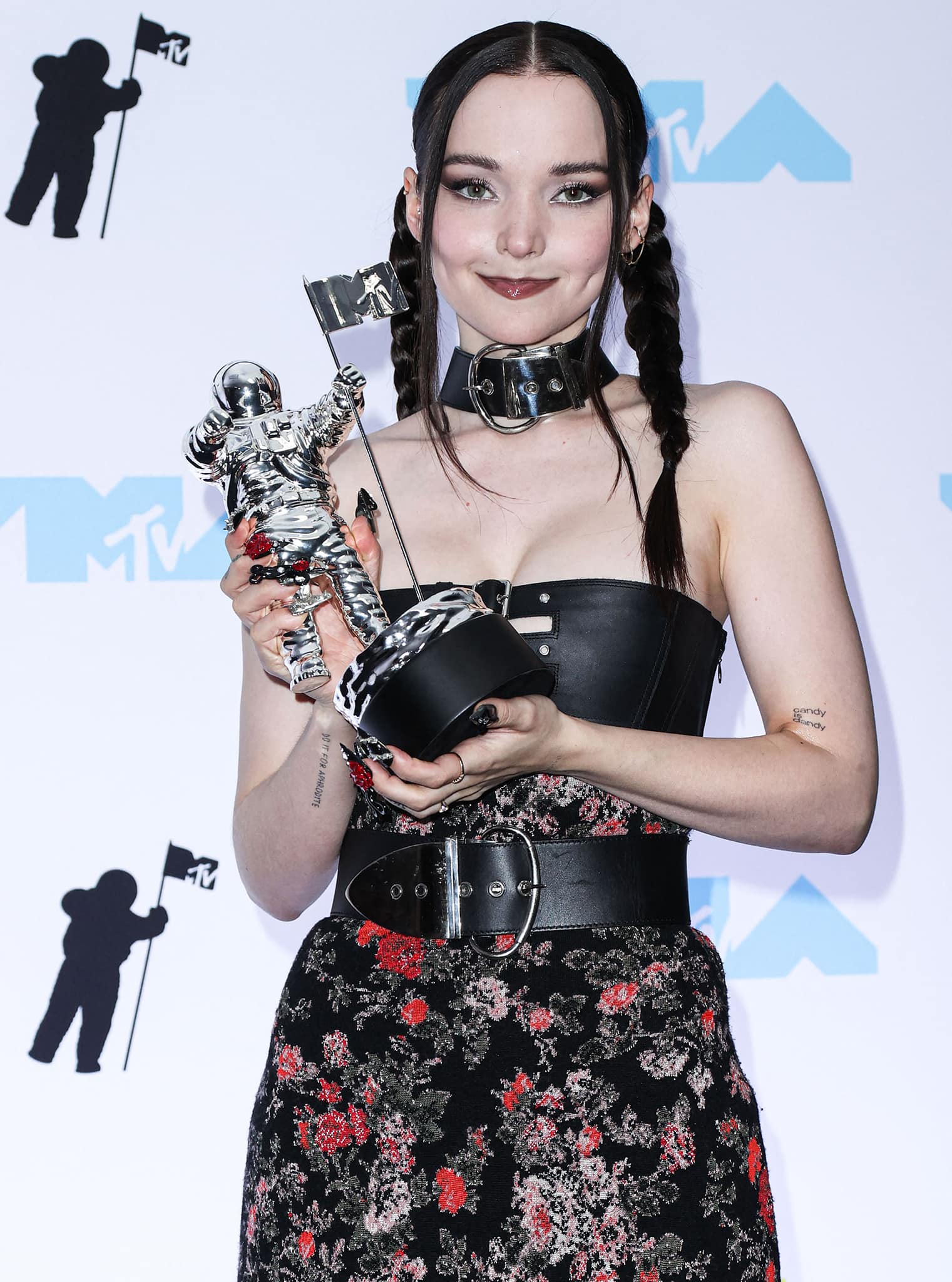 Best New Artist winner Dove Cameron styles her dark tresses in pigtail braids and wears gothic makeup with dark eyeshadow and mauve lipstick