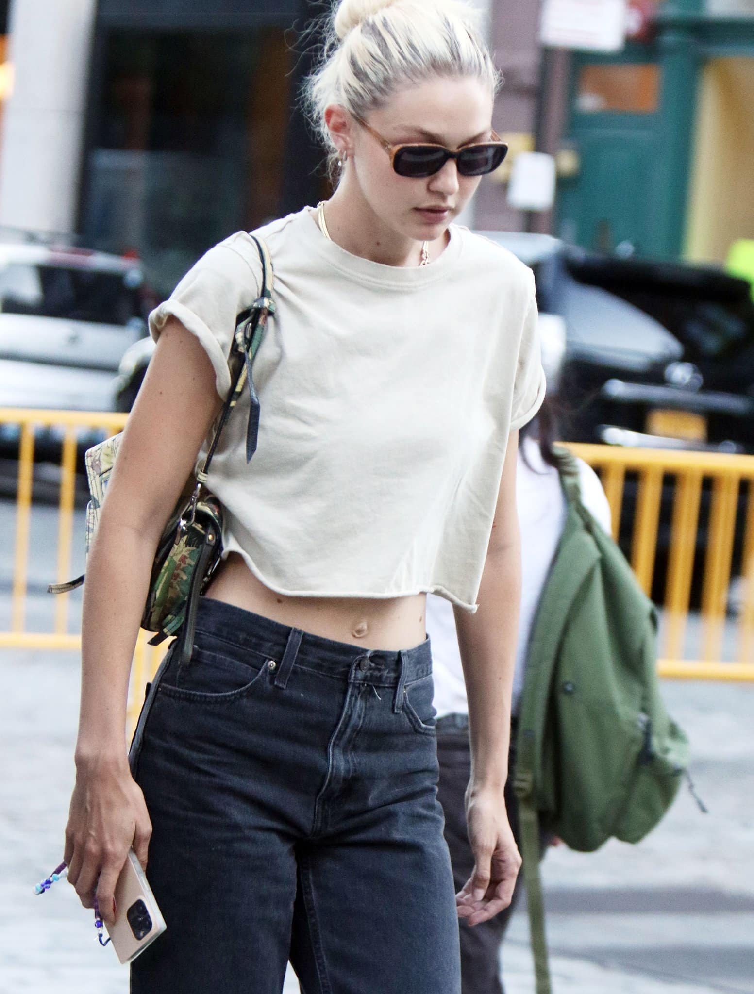 Gigi Hadid wears her hair in a casual bun and hides her eyes behind a pair of rectangular sunglasses