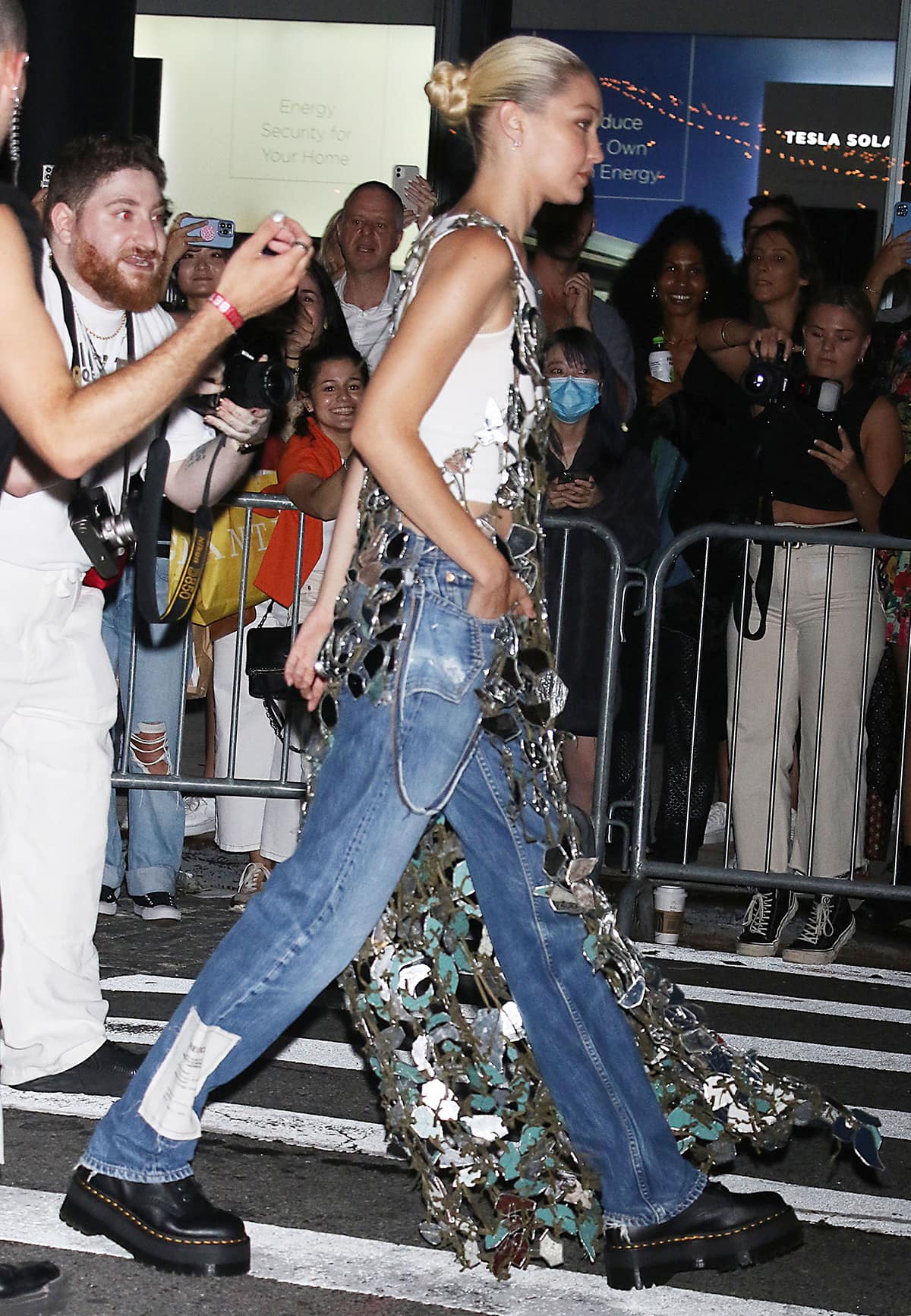 Gigi Hadid dons a chrome metal maxi dress over her tank top, baggy jeans, and Dr. Martens shoes