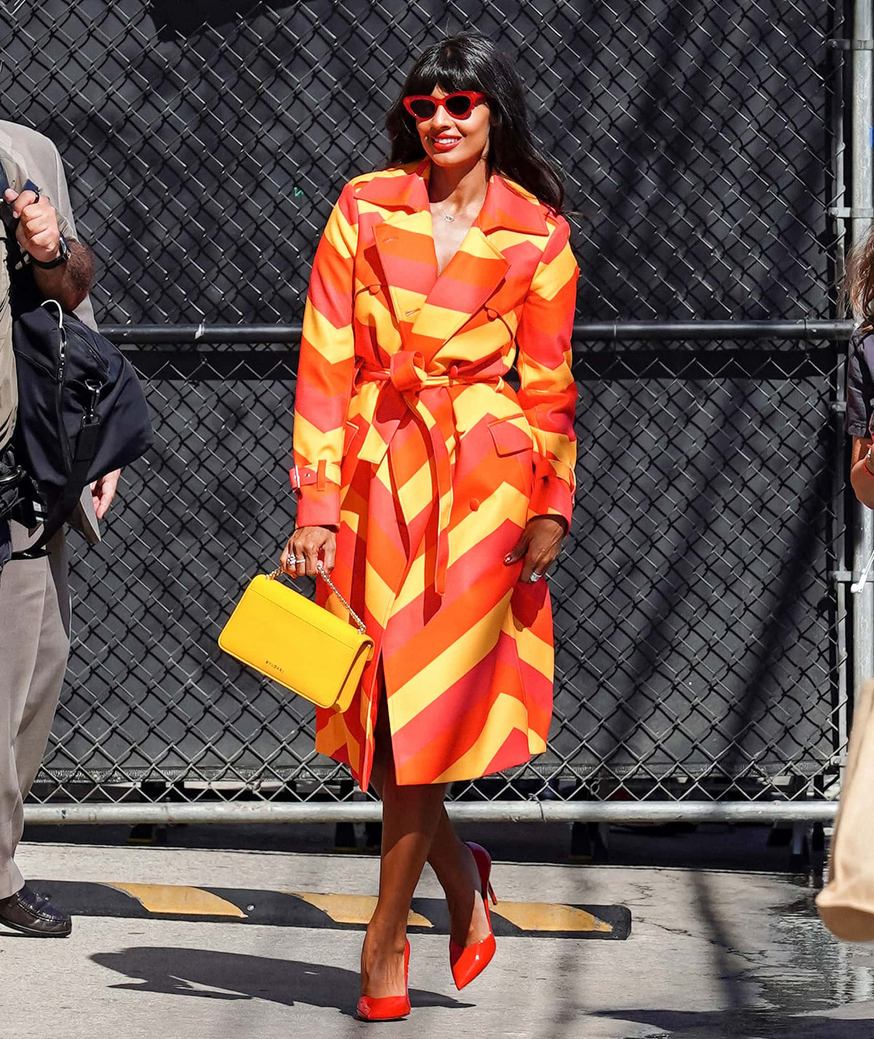 Jameela Jamil looks straight out of a comic book in a red, orange, and yellow chevron trench coat by Gray Scale IC