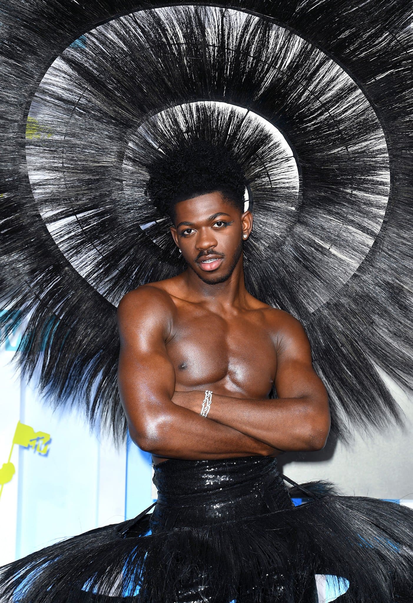 Lil Nas X styles his sculptural skirt with a matching feathered headpiece and De Beers diamond jewelry