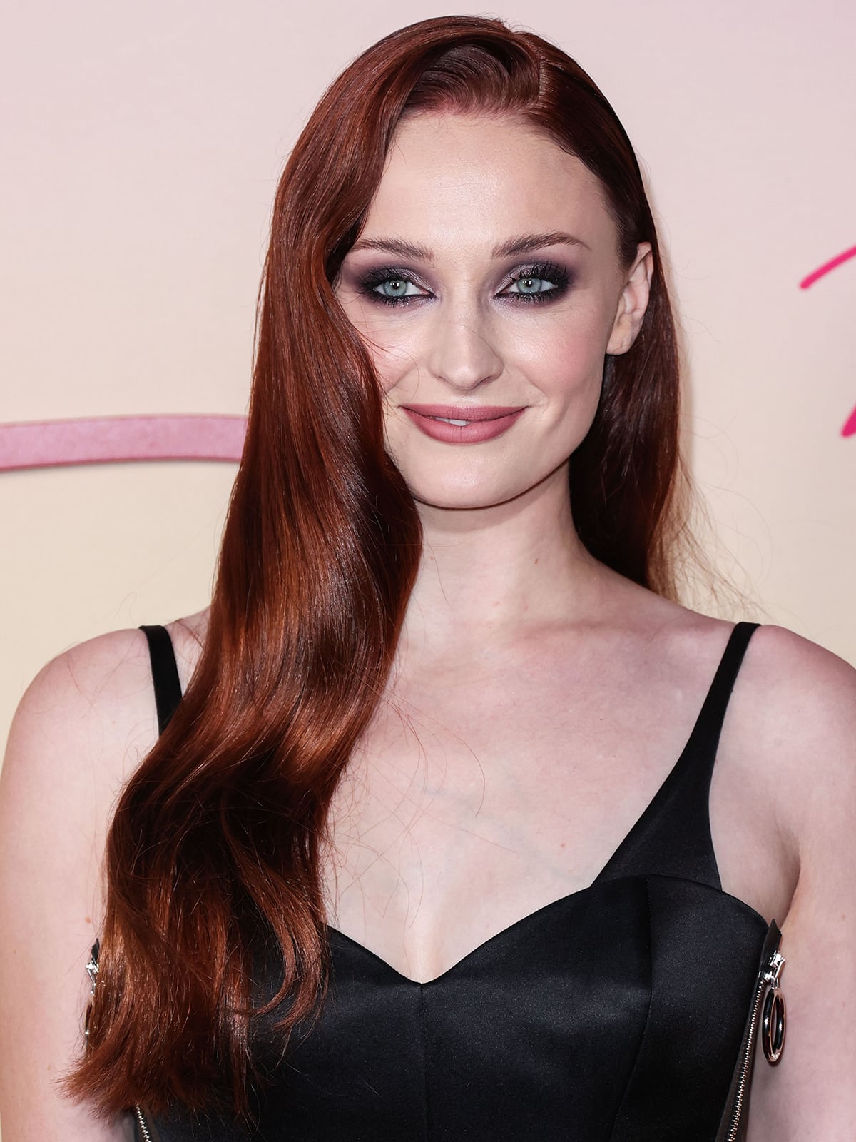 Sophie Turner creates a vampy look with smokey eyeshadow and long wavy red tresses