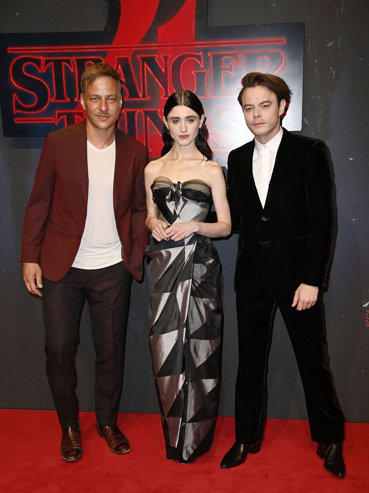 Natalia Dyer in a strapless Vivienne Westwood dress with her taller co-stars Tom Wlaschiha and Charlie Heaton at the screening of the Netflix series "Stranger Things" Season 4