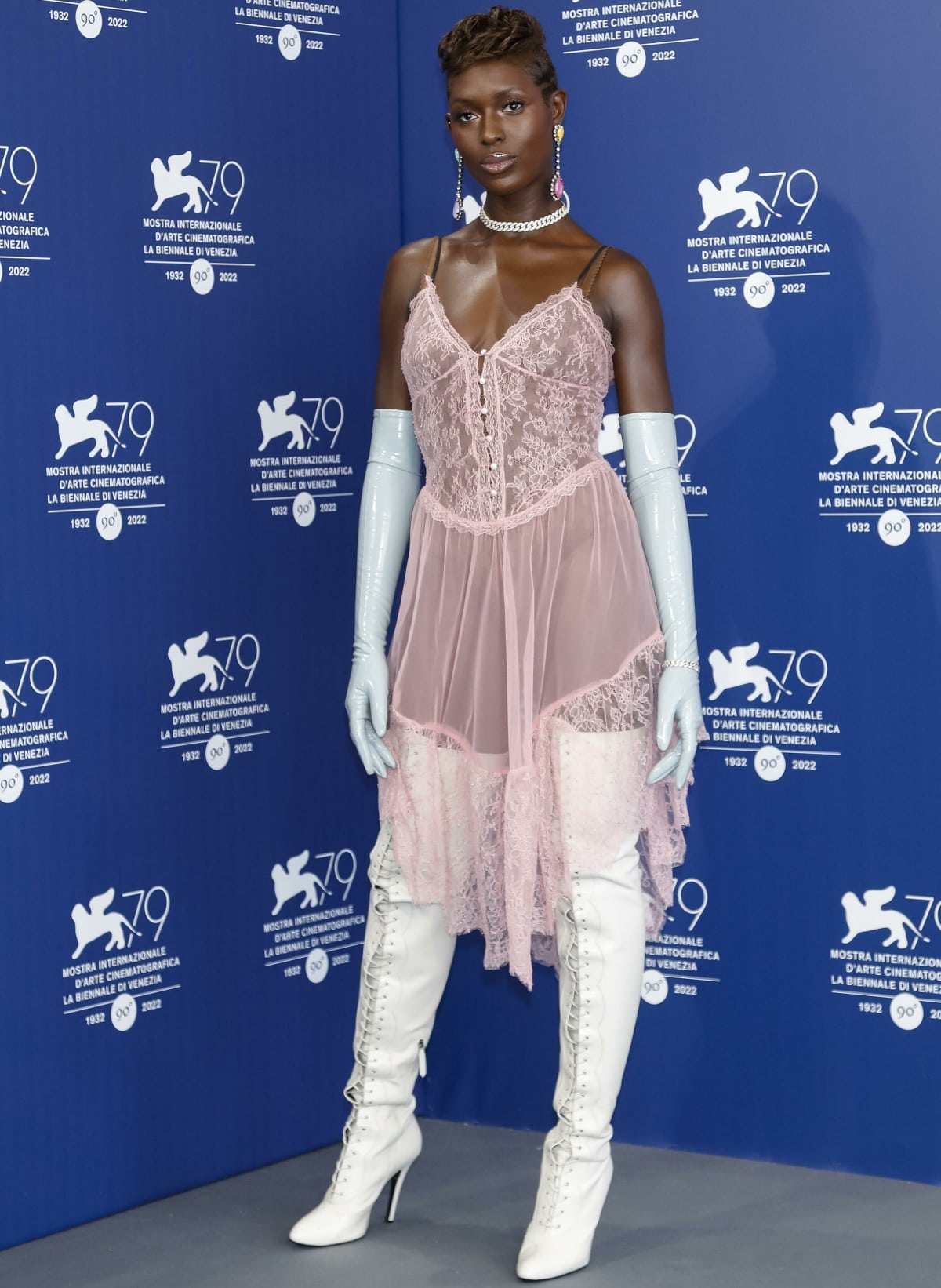 Jodie Turner-Smith wearing a Gucci pink lace slip dress with blue opera gloves and white thigh-high boots