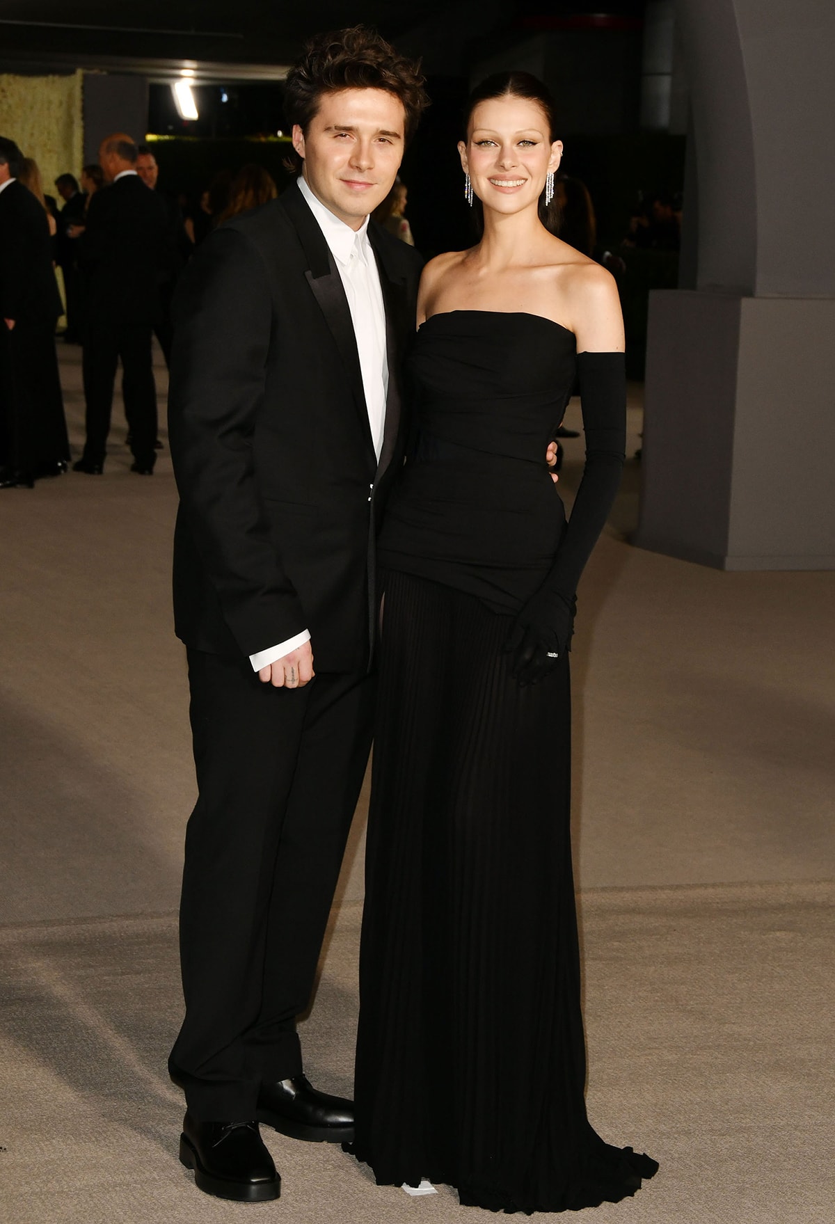 Brooklyn Beckham coordinates with wife Nicola Peltz, who dons a strapless black Givenchy gown with opera gloves