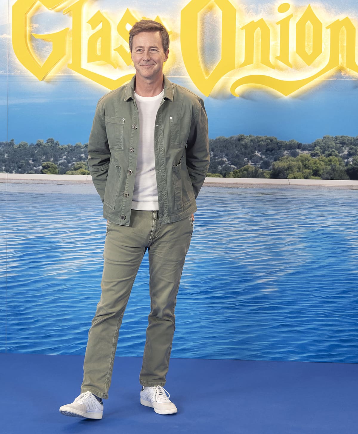 Edward Norton looks handsome in a relaxed khaki denim jacket, khaki jeans, and white sneakers