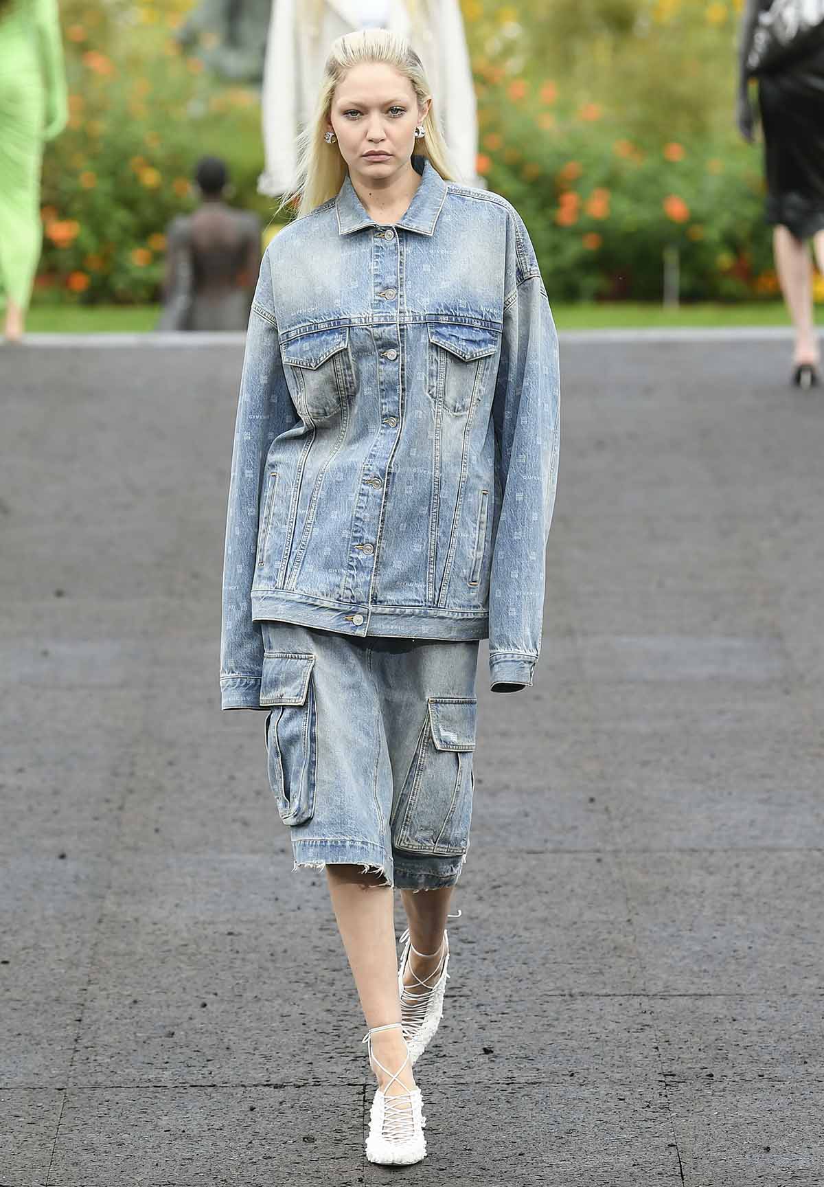 Gigi Hadid wears a denim-on-denim jacket and shorts outfit with bleached eyebrows and white lace-up heels at Givenchy's SS23 runway