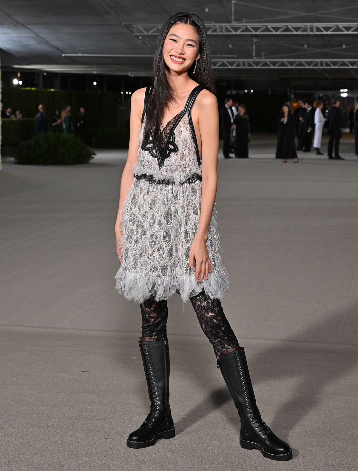 HoYeon Jung adds a rebellious touch to her feathered Louis Vuitton mini dress with lace tights and Territory Flat High Ranger boots