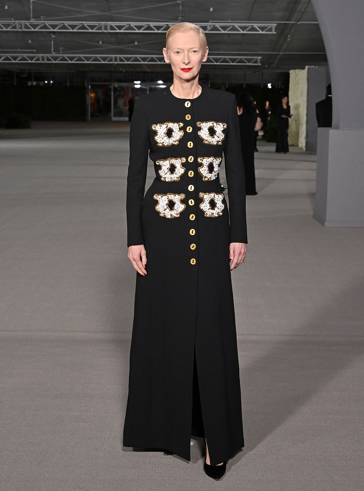 Tilda Swinton looks elegant in a Schiaparelli dress coat with teacup embroidered pockets and gold buttons