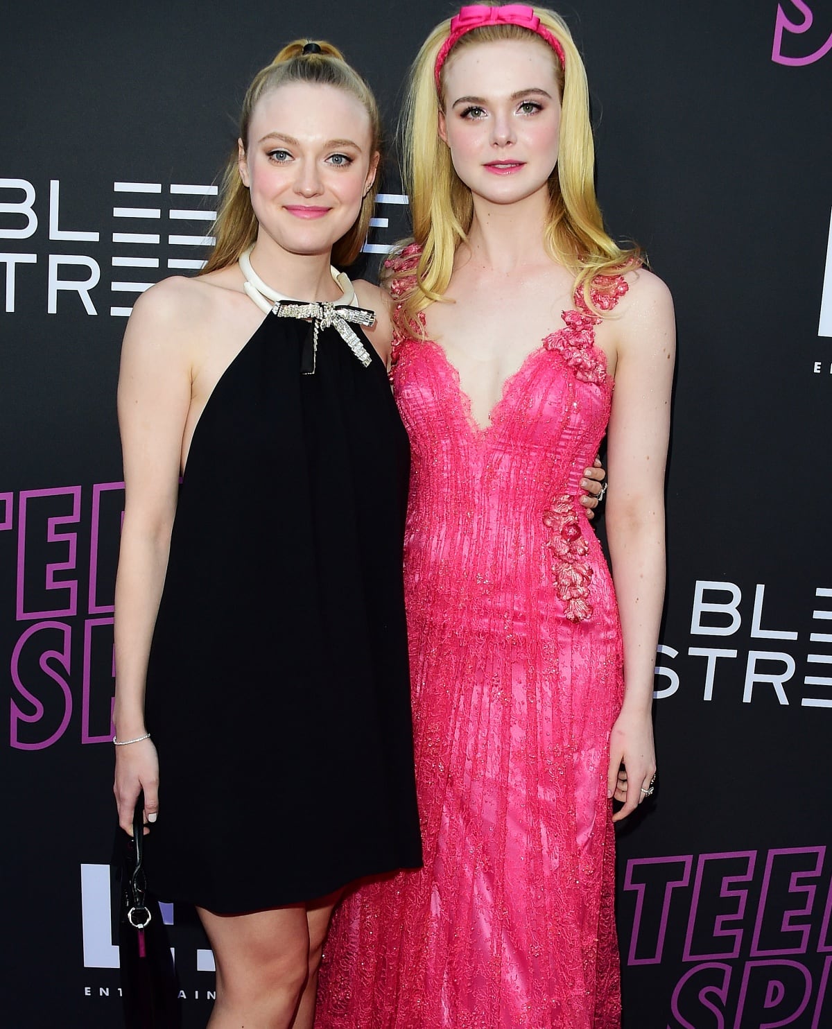 Dakota Fanning stuns in a chic black halter dress while Elle Fanning dazzles in a vibrant pink lace gown, both sisters making a stylish appearance at the Teen Spirit premiere