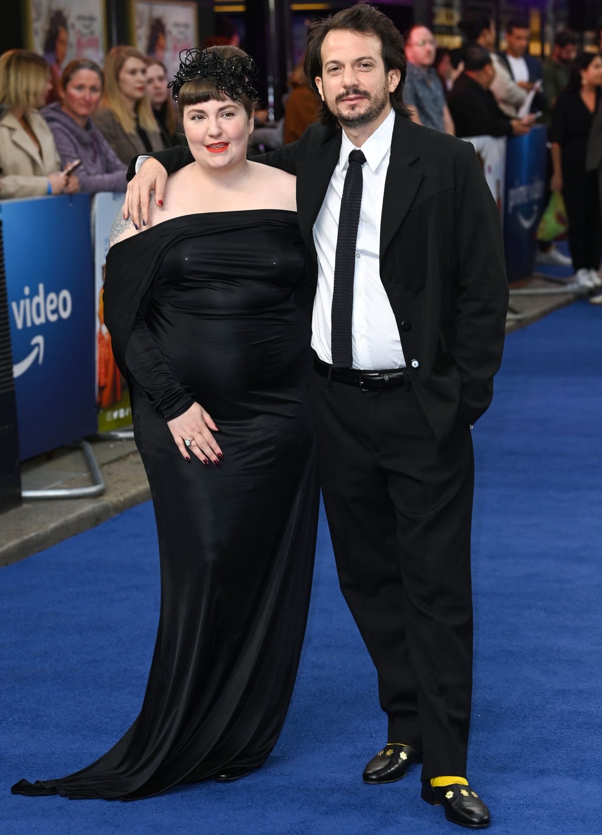 Lena Dunham wearing a custom black strapless gown by Factory New York and Luis Felber in a black suit with a crisp white shirt and a textured necktie at the London premiere of Catherine Called Birdy