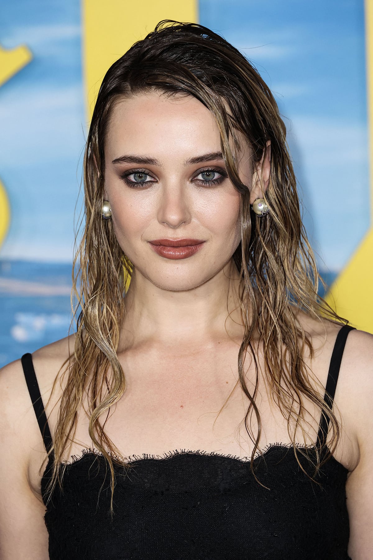 Katherine Langford keeps the glam-grunge vibe going with a wet-look hairstyle, smokey eyeshadow, eyeliner, and dark nude lipstick
