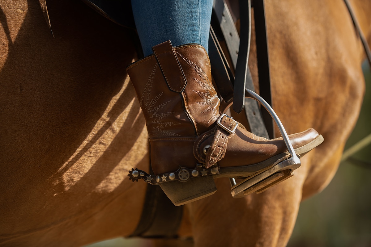 Cowboy boots in stirrup during horseback riding