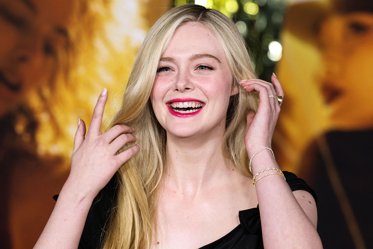 Elle Fanning parts her blonde hair to one side and wears soft makeup with vibrant fuchsia lipstick