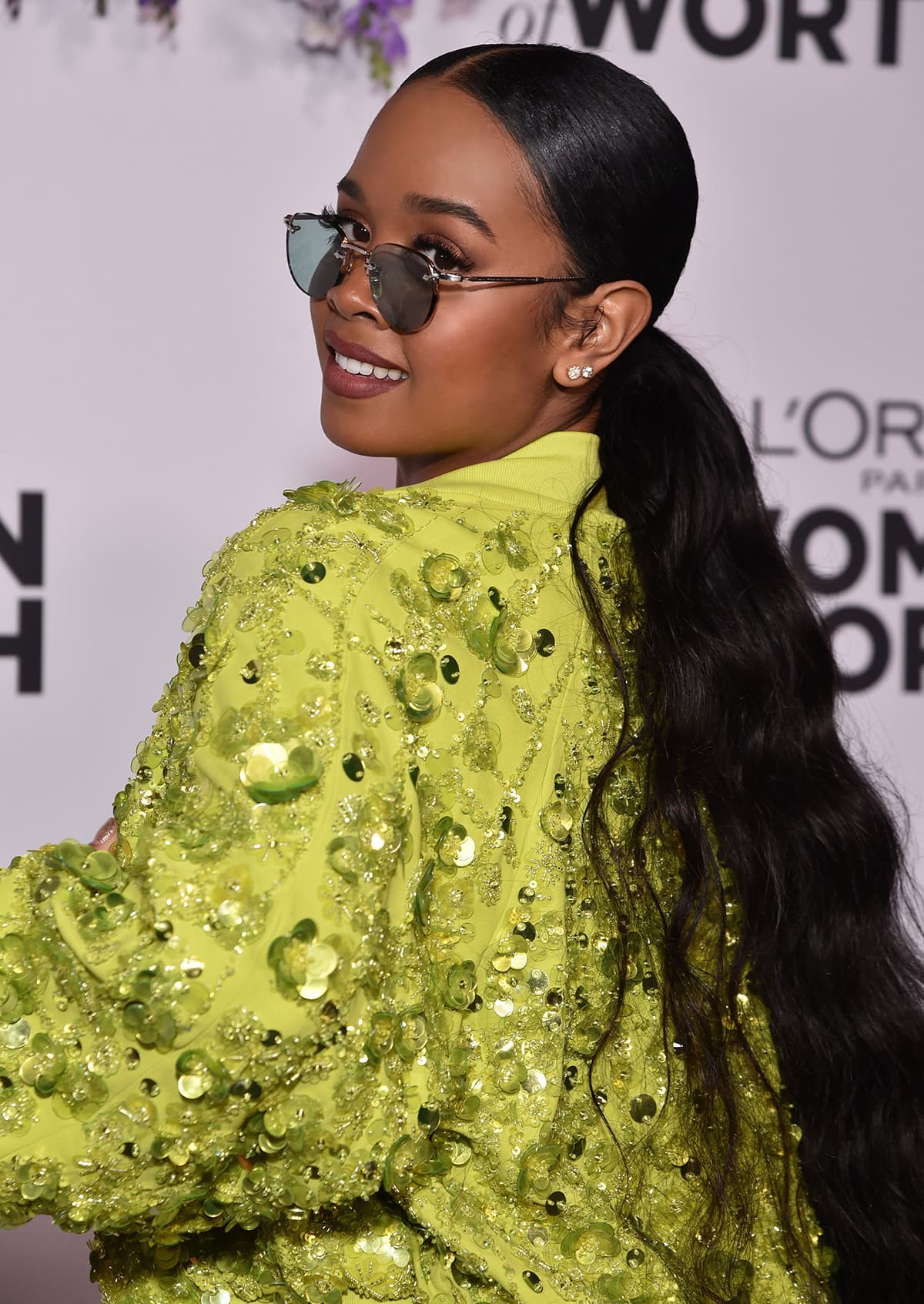 H.E.R. keeps the rest of her look simple with round sunglasses, diamond studs, and a ponytail
