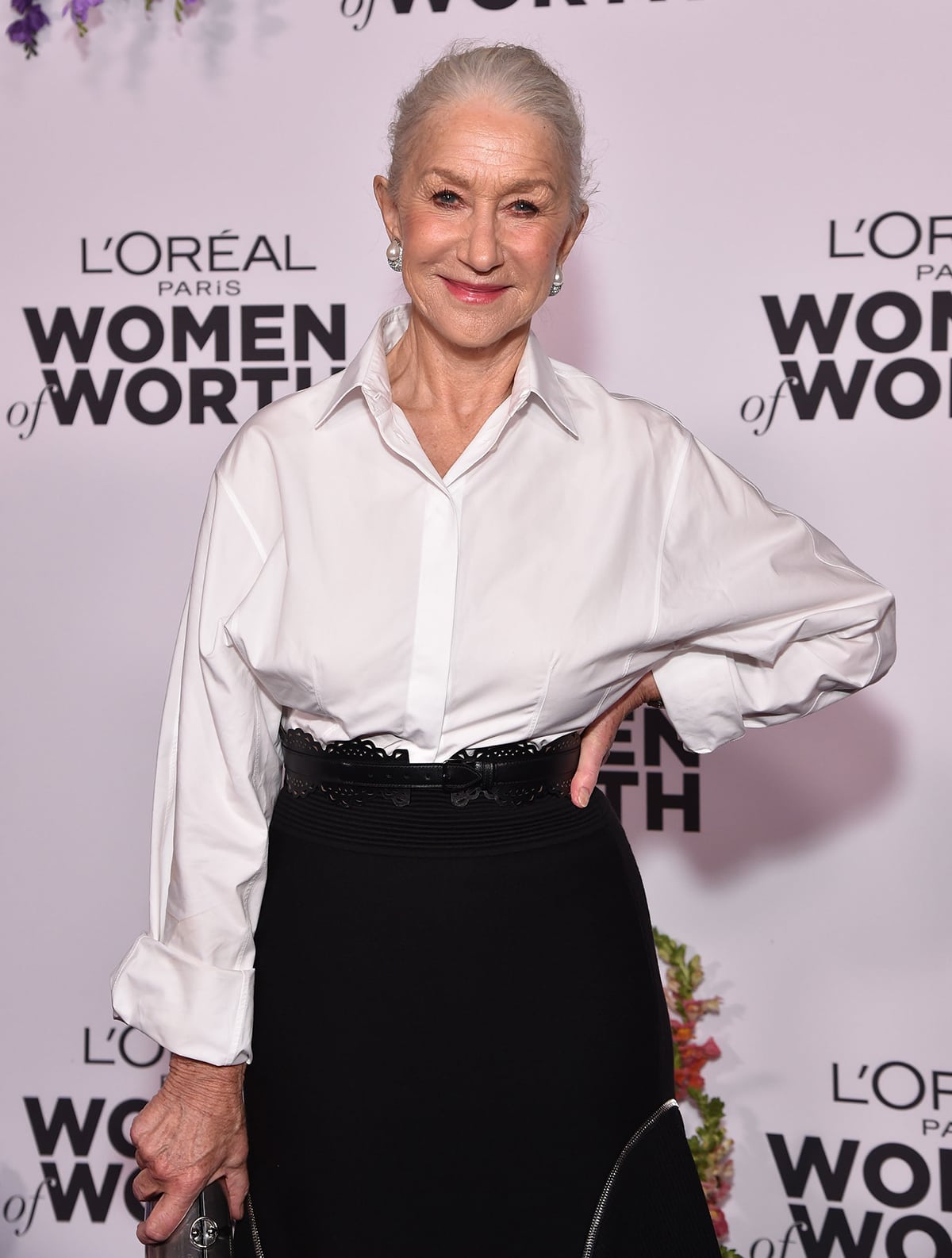 Helen Mirren styles her gray hair in a bun and adds a pop of color to her look with pink lipstick