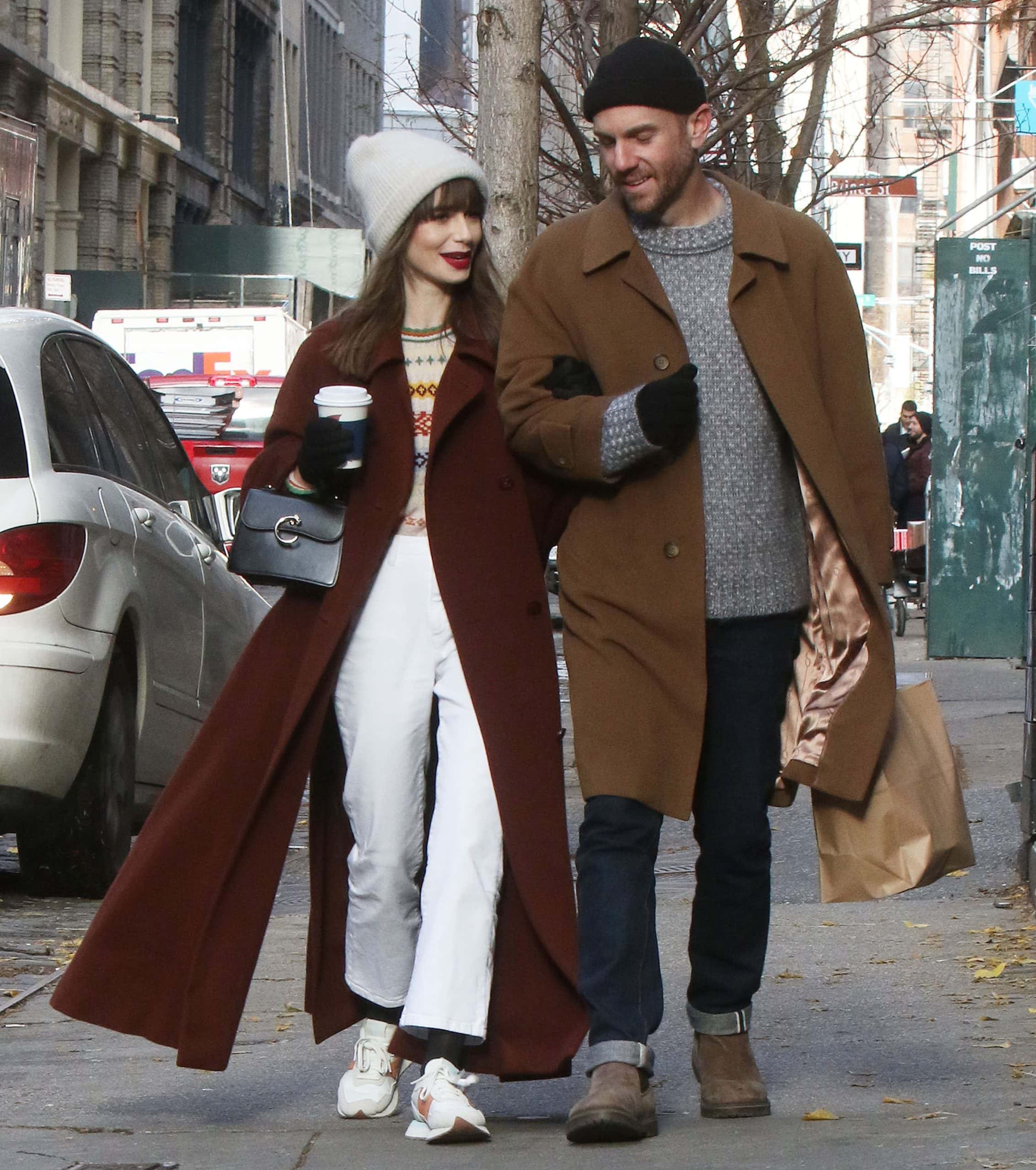 Lily Collins (L) with a Cartier top handle mini bag and her husband, Charlie McDowell, are seen in SoHo