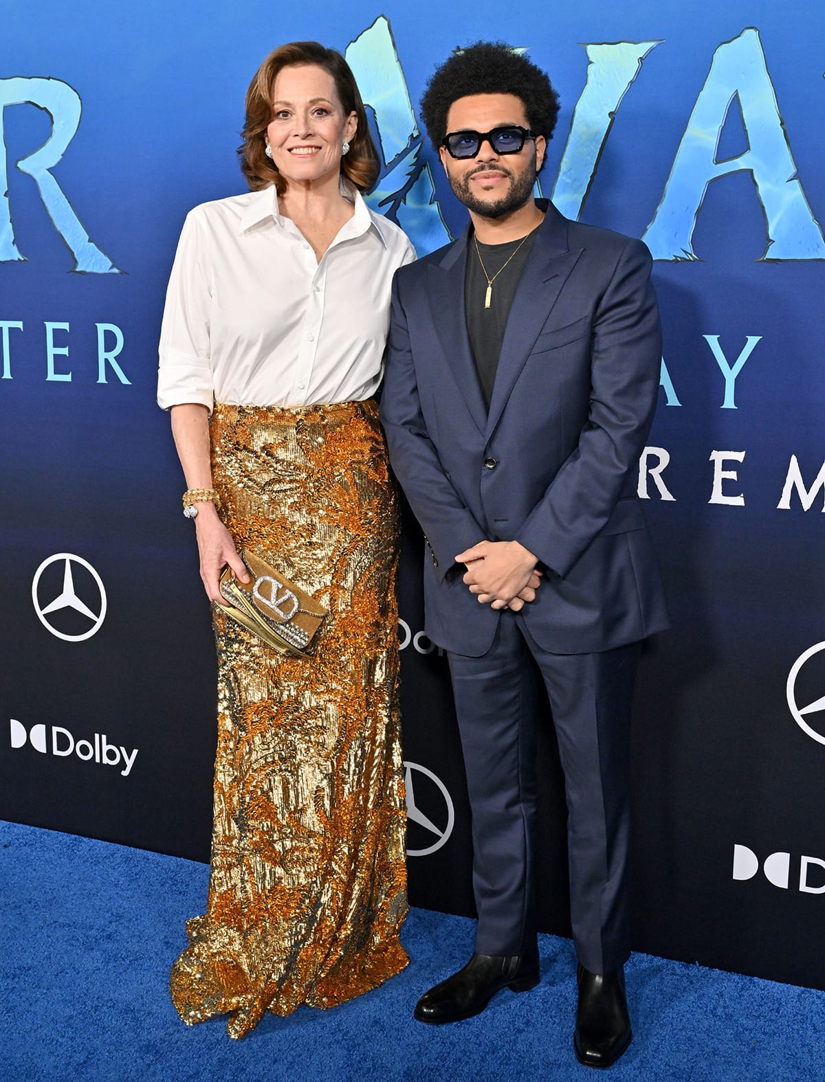 Sigourney Weaver poses with The Weeknd, who looks dapper in a navy suit with a black tee underneath