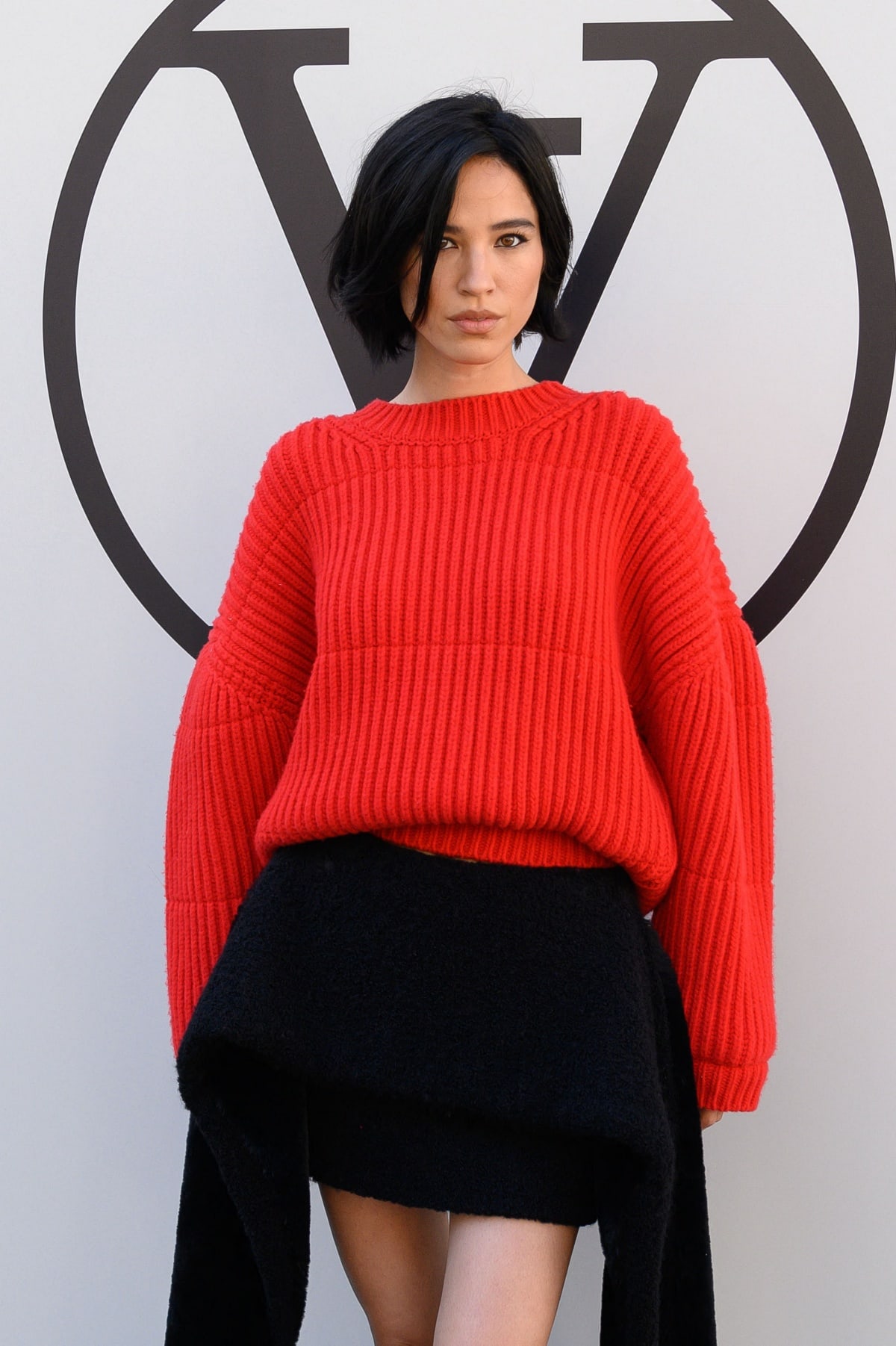 Kelsey Asbille makes a bold statement in a bright red oversized sweater paired with a chic black skirt