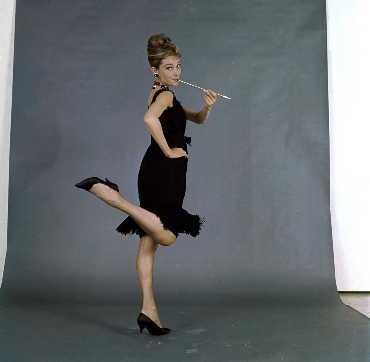 Audrey Hepburn’s Holly Golightly completes her iconic little black dress with black patent leather kitten-heel pumps by René Mancini, perfectly balancing elegance and ease