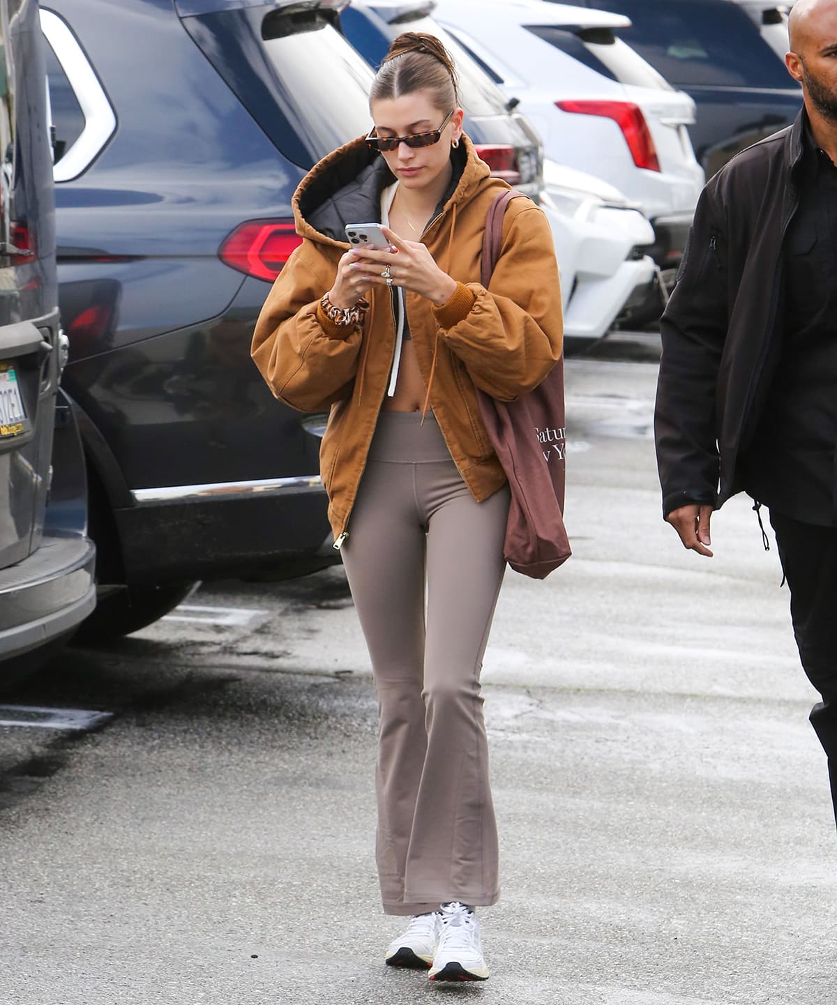 Hailey Bieber opts for a neutral Pilates outfit with TnAction TnaBUTTER bra top and leggings and R13 oversized workwear bomber jacket