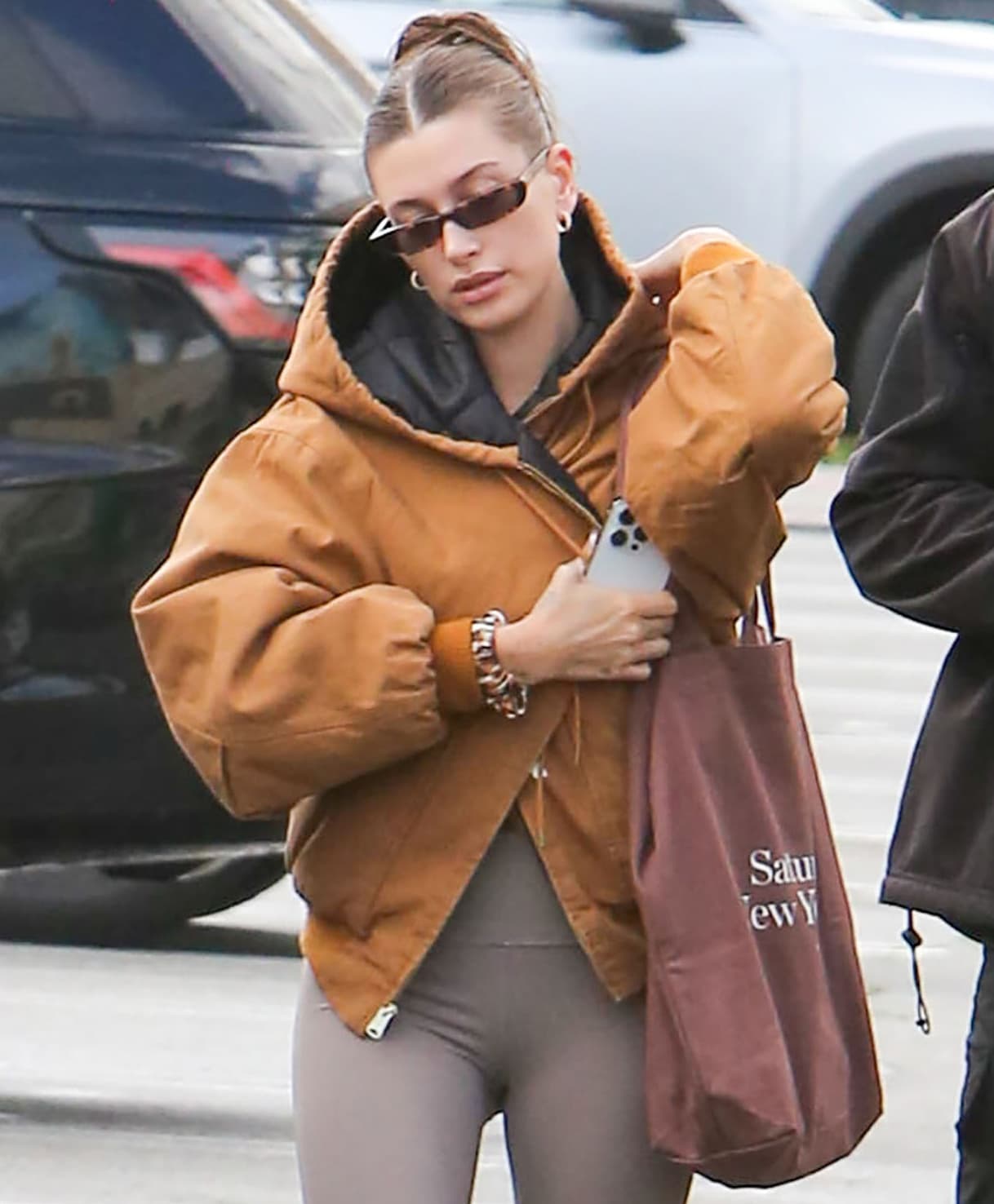 Hailey Bieber ties her hair in a bun with Emi Jay scrunchies and continues with the neutral theme of her look with The Attico tortoiseshell sunnies