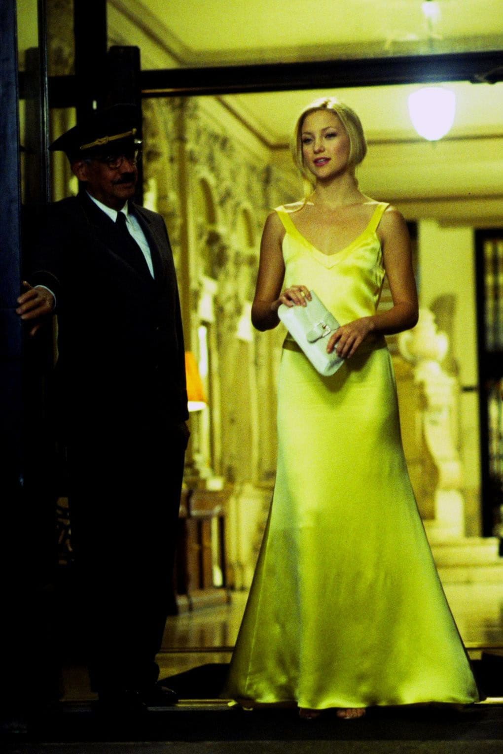 Kate Hudson dazzles as Andie Anderson in How to Lose a Guy in 10 Days, wearing a silky yellow slip gown by Dina Bar-el paired with strappy metallic heels and a white satin clutch for a showstopping entrance