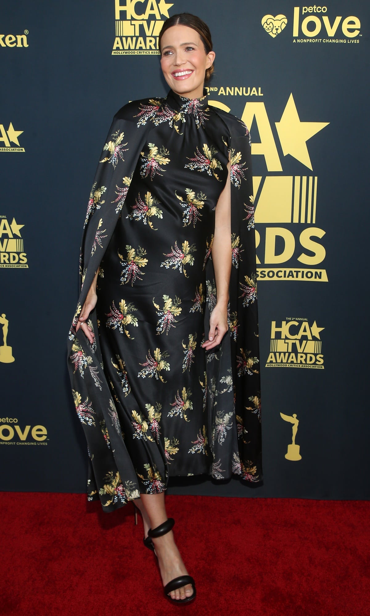 Mandy Moore displayed her style in a black silk dress with elegant floral patterns and caped sleeves at the 2nd Annual HCA TV Awards