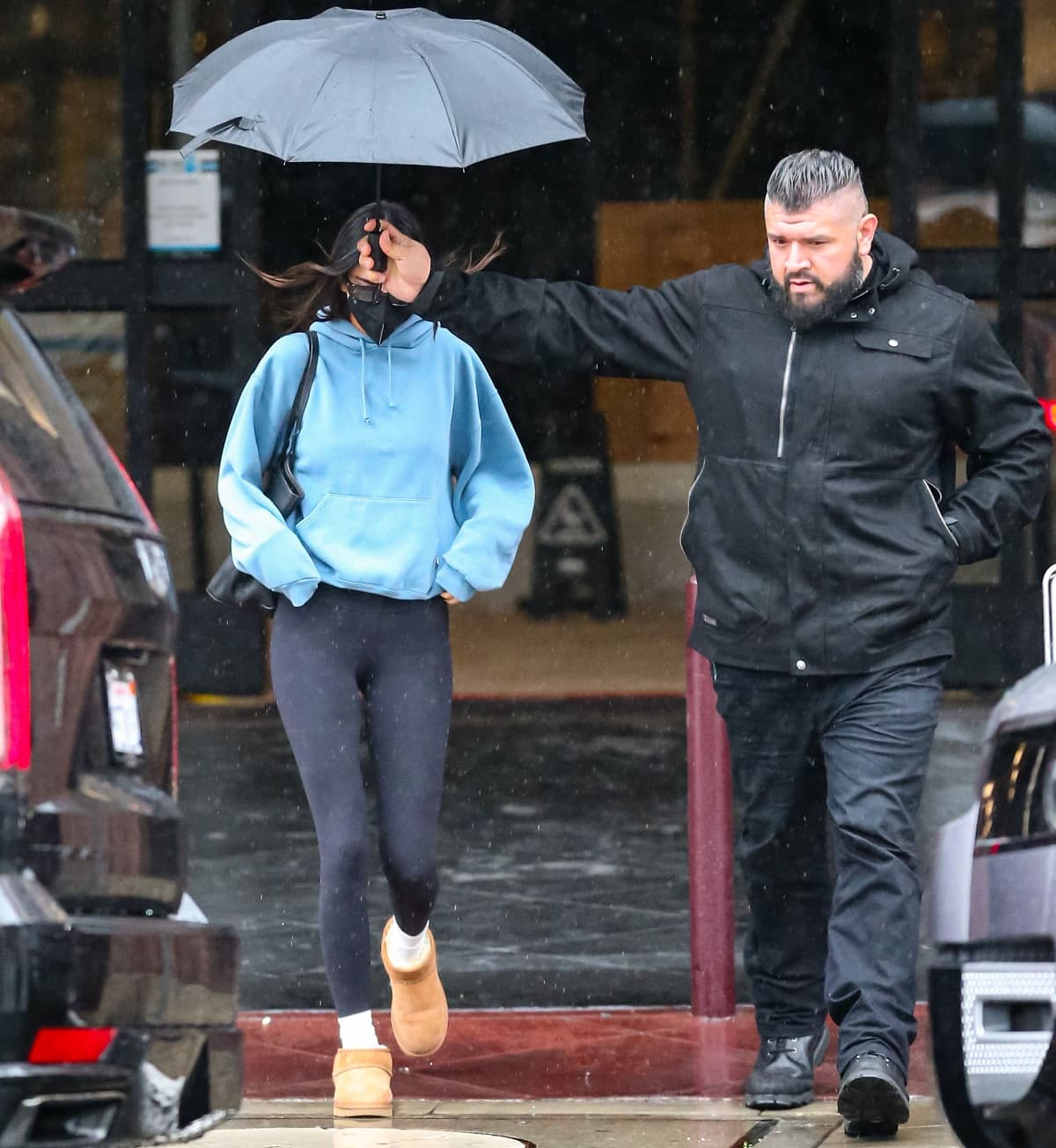 Kendall Jenner out in the pouring rain with her bodyguard holding out the umbrella for her