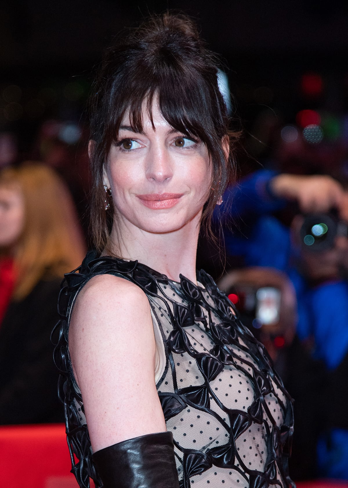Anne Hathaway wears a see-through Valentino dress with leather bows, leather gloves, and Nite-Out Satin pumps