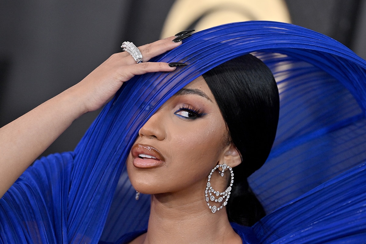 Cardi B wears fake lashes, satin lipstick, and blue eyeliner by Pat McGrath and styles her hair in a neat low bun