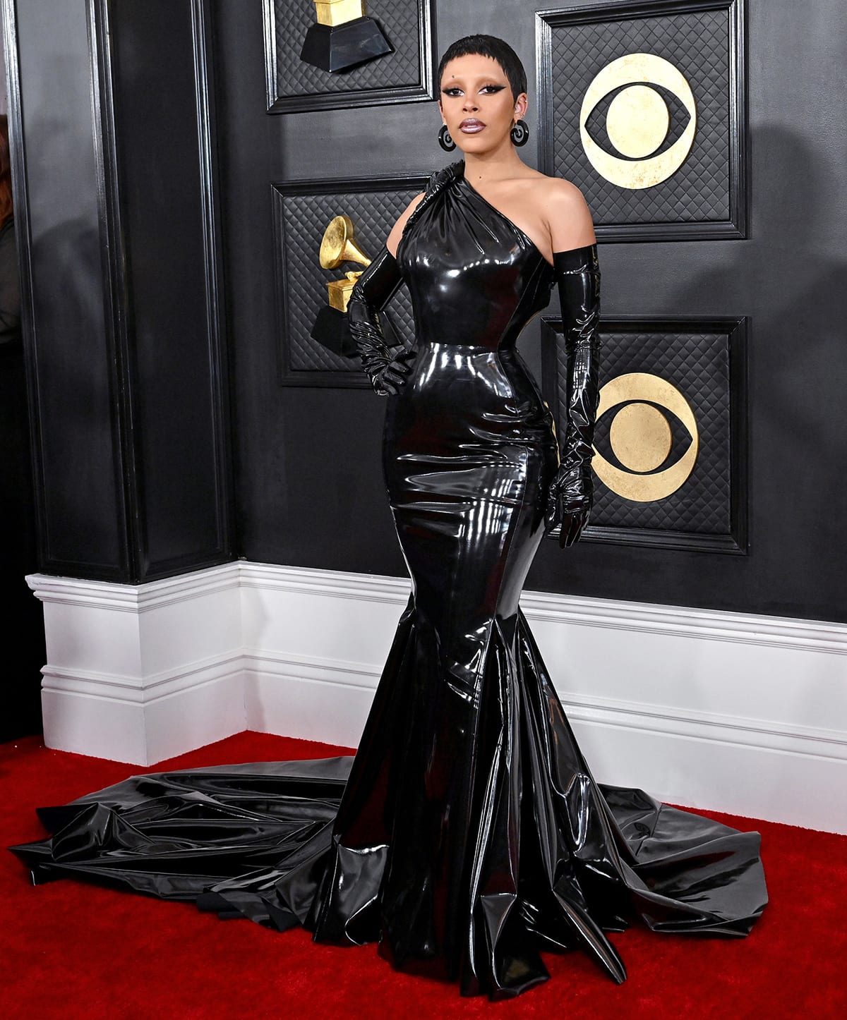 Doja Cat flaunts her hourglass figure in a custom Versace black vinyl one-shoulder gown with matching opera gloves