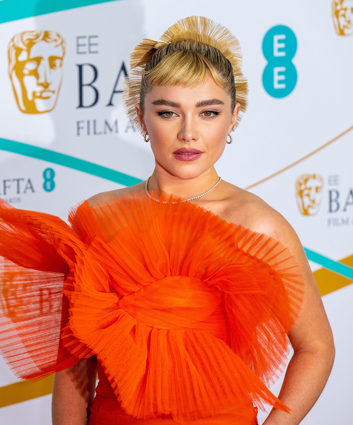 Florence Pugh coordinates her glam with her gown by wearing a fanned-out updo and Audrey Hepburn-inspired brushed up brows